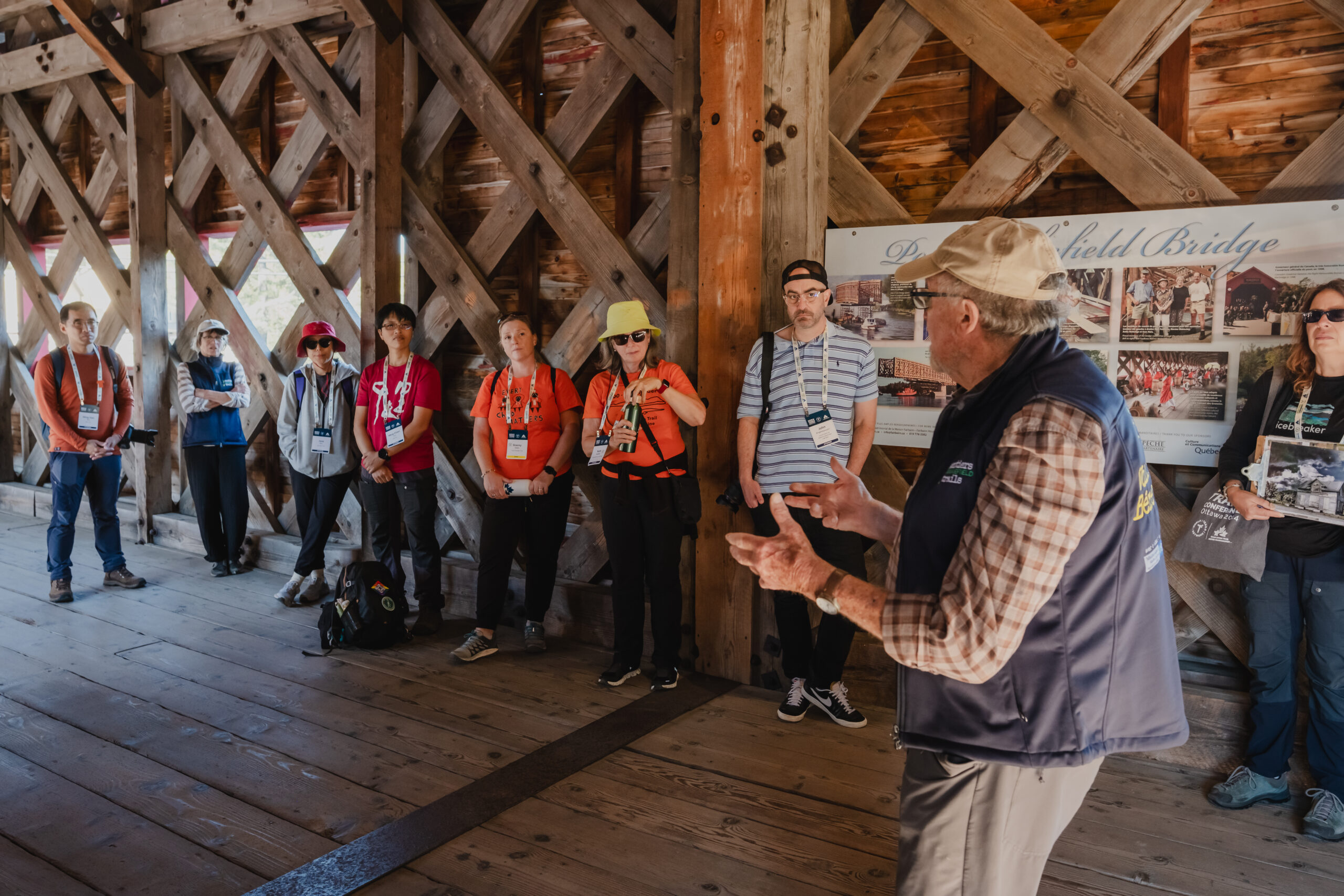 A person leads a presentation on a covered bridge along the trail.